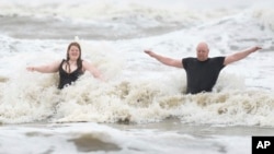 Jeremy Reddout y su hija, Elexus, disfrutan de las olas entre Murdoch's y Pleasure Pier mientras llueve en Galveston, Texas, el 19 de junio de 2024.