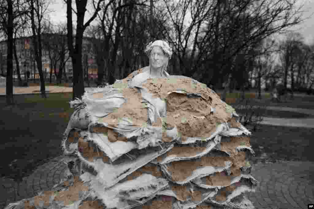Una estatua, cubierta de sacos de arena para protegerla de los bombardeos rusos en Kiev, Ucrania, el 9 de marzo de 2023. Hay sacos de arena protegiendo estatuas y barreras antitanque en las calles, trincheras en los bosques cercanos y avisos de minas terrestres en el monte. Las señales pintadas en las paredes indican el refugio más próximo, mientras las sirenas antiaéreas suenan ocasionalmente en la ciudad, que a veces sufre ataques con misiles.
