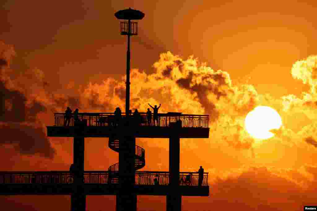 Revelers celebrate the sunrise during the July Morning festival at the pier of Burgas, on the Black Sea coast, Bulgaria.