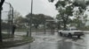 Un transeúnte se refugia bajo un paraguas mientras camina por una acera de Caracas durante una lluvia, el martes 30 de mayo de 2023.