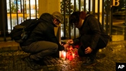 A woman lights candles near the philosophy building at Charles University in Prague, Czech Republic, Dec. 21, 2023. A Czech student on Thursday shot and killed his father, then shot and killed at least 14 people at the university, police said. His body was found at the scene. 
