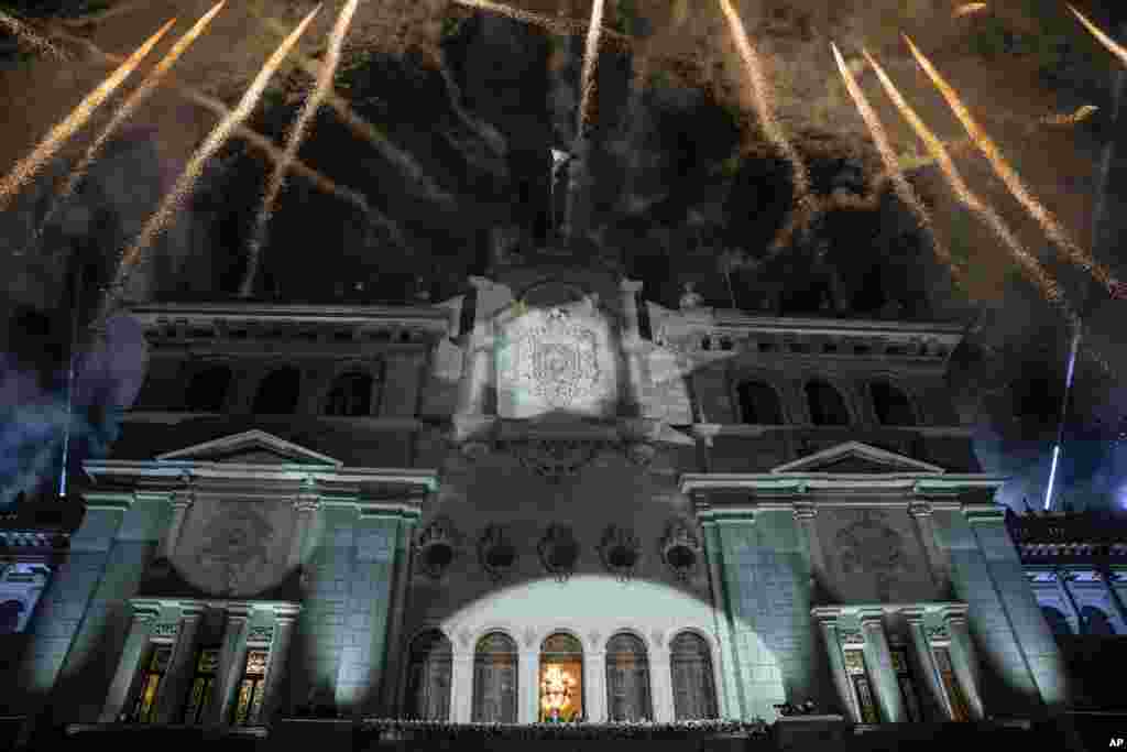 Los fuegos artificiales explotan sobre el Palacio Nacional mientras el presidente entrante de Guatemala, Bernardo Arévalo, y la vicepresidenta Karin Herrera saludan a sus partidarios desde el balcón, el día de su toma de posesión en la Ciudad de Guatemala, en la madrugada del 15 de enero de 2024. (Foto AP/Santiago Billy) 