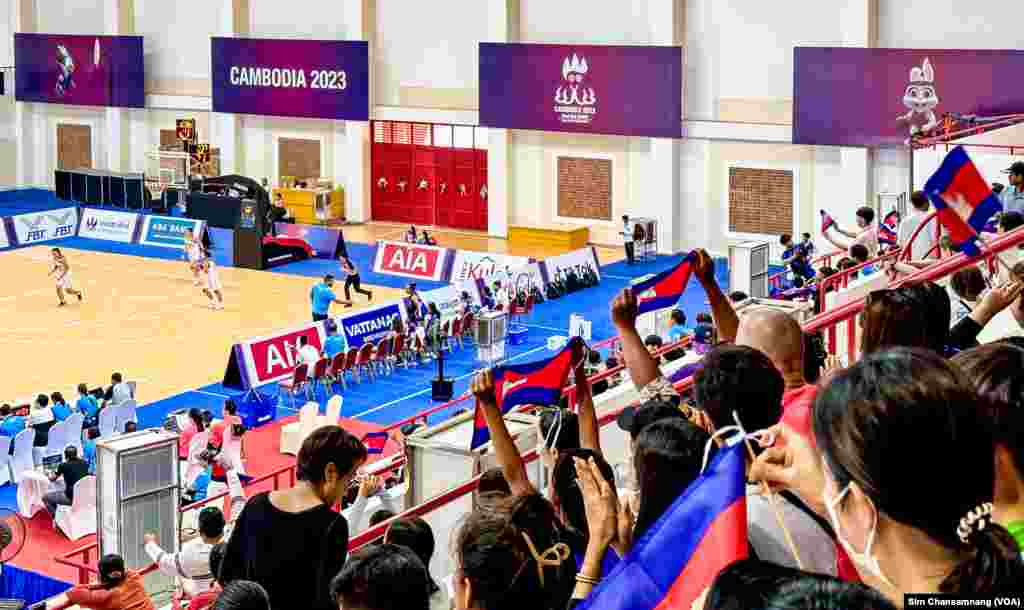 អ្នកគាំទ្ររបស់កម្ពុជាលើកទង់ជាតិកម្ពុជា ក្នុងពេលប្រកួតកីឡាបាល់បះ នារី នៃការប្រកួតកីឡាស៊ីហ្គេមលើកទី៣២ នៅពហុកីឡដា្ឋនមរតកតេជា ក្នុងរាជធានីភ្នំពេញ នៅថ្ងៃទី១៣ ខែឧសភា ឆ្នាំ២០២៣។ (ស៊ឹម ចាន់សំណាង/វីអូអេ)
