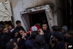 Mourners carry the body of Montaser Shawwa, 16, out of the family house, during his funeral in the West Bank refugee camp of Balata, Nablus, Tuesday, Feb. 21, 2023.