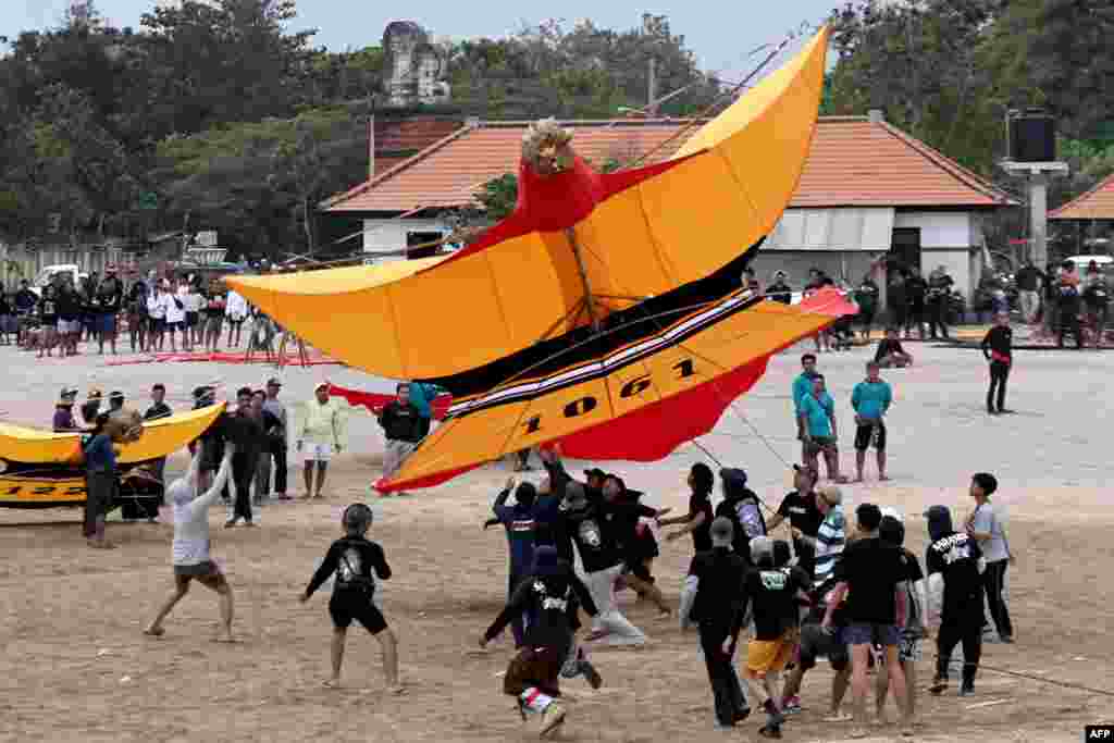 Participants launch a giant kite during the Bali Kite Festival at Mertasari beach in Sanur, Indonesia's Bali island.