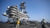El personal de la cabina de vuelo pasa frente a los aviones a bordo del portaaviones USS GW Bush que navega en el mar Mediterráneo, el lunes 17 de octubre de 2022.