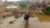 A woman sorts through floodwaters at her damaged home near Abu Hamdan, Sudan, on Aug. 7, 2024.