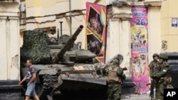 FILE - Russian servicemen guard an area standing in front of a tank in a street in Rostov-on-Don, Russia, June 24, 2023. 