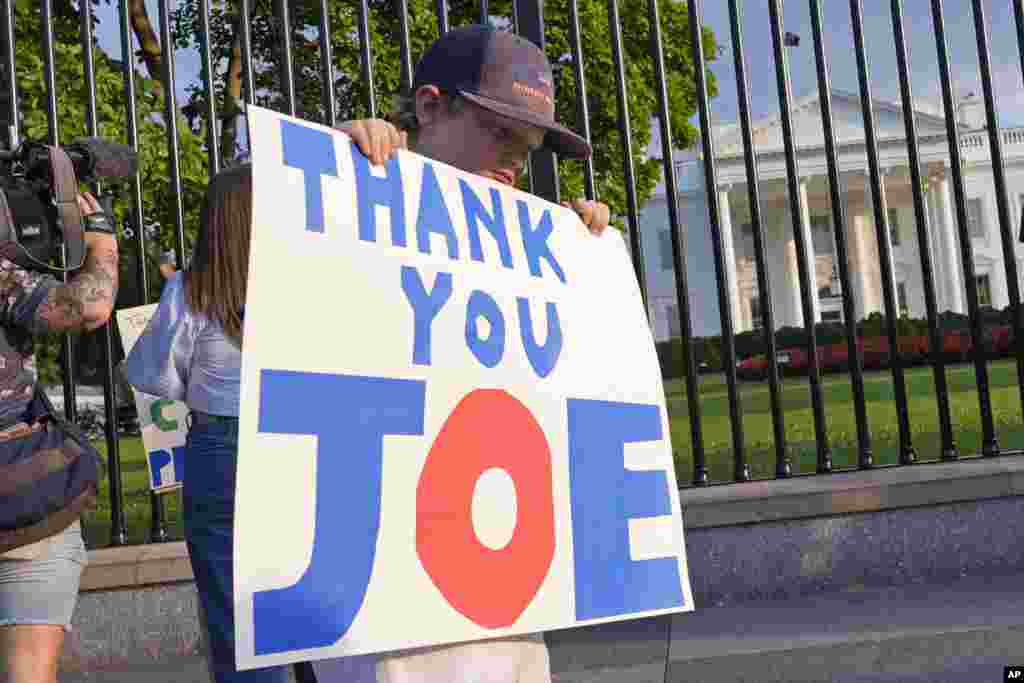 Hugh Kieve, de 10 años, sostiene un cartel frente a la Casa Blanca con la frase "Gracias, Joe" mientras él y su familia salen a mostrar su apoyo al presidente Joe Biden.