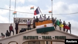 Men hold Niger and Russian flags as they gather with thousands of anti-sanctions protesters in support of the putschist soldiers in the capital Niamey, Niger, Aug. 3, 2023.