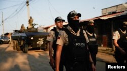 ARCHIVO - Policía caminan delante de un vehículo militar blindado durante una operación conjunta militar y policial conjunta en Guayaquil, Ecuador, el 26 de marzo de 2024, esta ciudad se ha convertido en el epicentro de combates contra estructuras del crimen organizado.