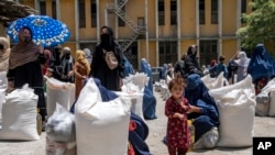 FILE - Afghan women receive food rations distributed by a humanitarian aid group, in Kabul, Afghanistan, May 28, 2023.