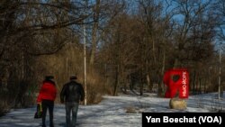 Una pareja pasa por un hito que celebra el amor de los ciudadanos por la pequeña ciudad de primera línea de Nueva York en la región de Donetsk, Ucrania, el 20 de febrero de 2023.