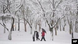 People walk through the snow in Goyang, South Korea, Saturday, Dec. 30, 2023. South Korean Meteorological Administration issued a heavy snow advisory for some parts of the Korea peninsula. 