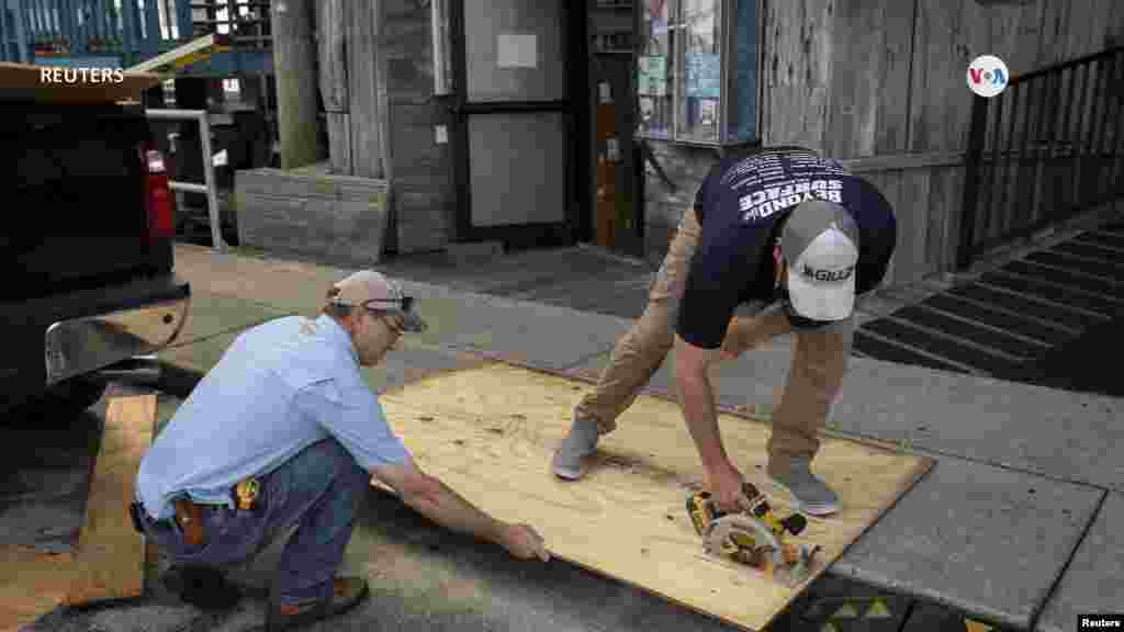 Los comerciantes de la Florida ponen madera contrachapada en las ventanas de sus tiendas previa a la llegada del ciclón. 