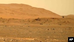 FILE - This April 30, 2021, image taken by the Mars Perseverance rover shows the Ingenuity helicopter, right, flying over the surface of the planet. Data gathered from the rover have confirmed that lake sediments existed on Mars. (NASA via AP)