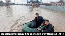 This photo released by the Russian Emergency Situations Ministry on April 6, 2024, shows rescuers wading across a flooded street on their way to evacuate residents in the Orenburg region, southeast of the southern tip of the Ural Mountains, Russia.