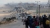 Palestinians, who were displaced by Israel's military offensive on south Gaza, make their way as they attempt to return to their homes in north Gaza through an Israeli checkpoint, as seen from central Gaza Strip April 15, 2024. 
