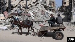 Niños palestinos en un carro tirado por un burro cerca de un edificio destruido por un bombardeo israelí en Ráfah, en el sur de la Franja de Gaza, el 31 de marzo de 2024.