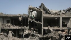 Palestinians look at the destruction after an Israeli strike on a residential building in Nuseirat Refugee Camp, Gaza Strip, May 19, 2024.