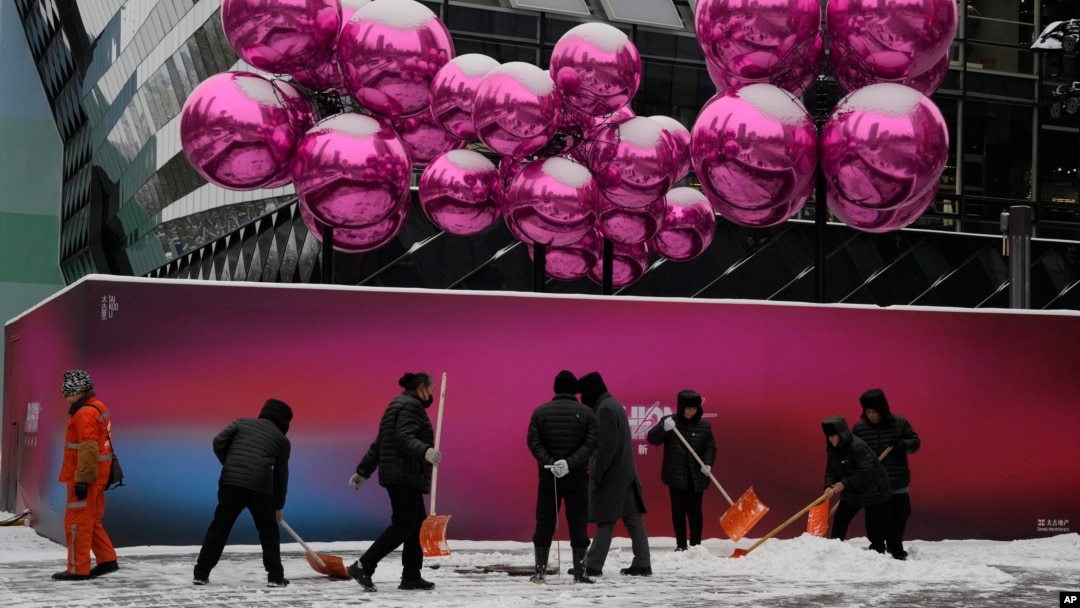 北京一家已經為聖誕節裝飾起來的商場外工人們正在清除積雪。 （2023年12月14日）