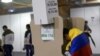 ARCHIVO - Un votante envuelto en la bandera nacional llena una papeleta en una mesa electoral dentro de Corferias durante la segunda vuelta de las elecciones presidenciales en Bogotá, Colombia, el 19 de junio de 2022.