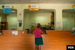 A Kupiansk resident defies the constant shelling to get to the post office on Aug. 21, 2023. (Yan Boechat/VOA)