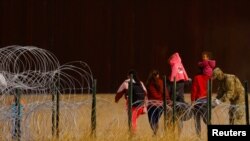 Un miembro de la Guardia Nacional de Texas coloca alambre de púas a orillas del río Bravo, frontera entre EEUU y México, con el propósito de reforzar la seguridad fronteriza e inhibir el cruce de migrantes. Visto desde Ciudad Juárez, México, el 13 de abril de 2023.