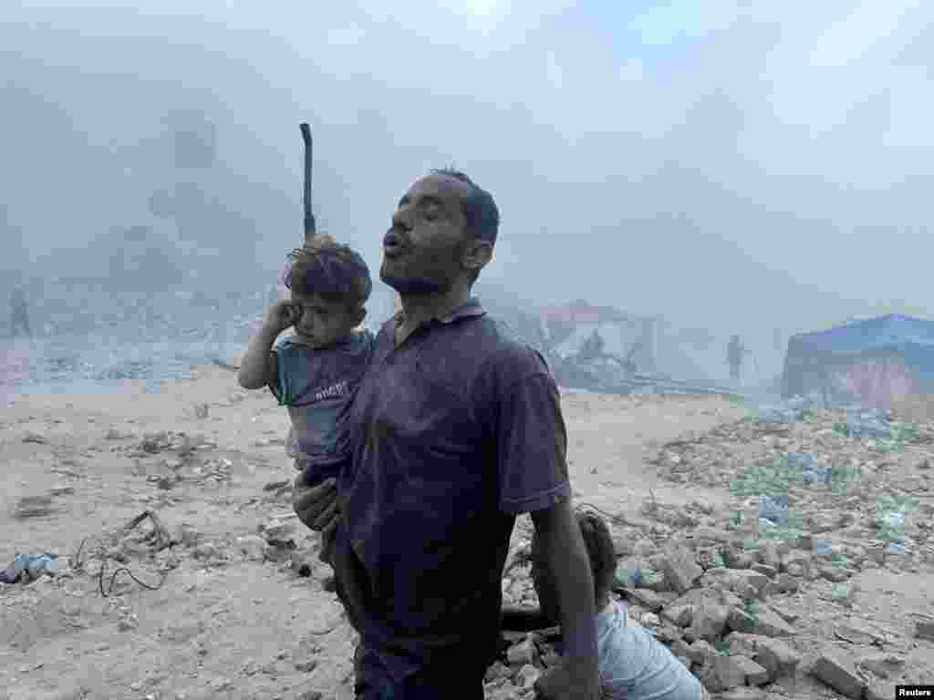 A Palestinian man carries a child, following an Israeli strike near a U.N.-run school sheltering displaced people, amid the Israel-Hamas conflict, in Khan Younis, in the southern Gaza Strip.
