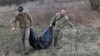 Miembros de un equipo ucraniano especial retiran los restos de un soldado ruso encontrado en la aldea de Synykha, en la región de Járkov, el 8 de abril de 2023.