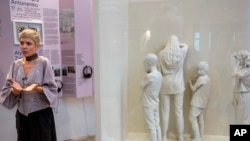 Katya Taylor, the curator of the War Diaries exhibition, which showcases the personal diaries of Ukrainian children who have witnessed the war, talks next to an artwork by Pavla Nikitina at Amsterdam city hall, Netherlands, Aug. 17, 2023.
