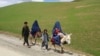 Mujeres afganas vestidas con burka montan en burro junto a niños en una carretera cerca de la aldea de Shah Mari en el distrito de Argo, provincia de Badakhshan, Afganistán, el 1 de mayo de 2024.
