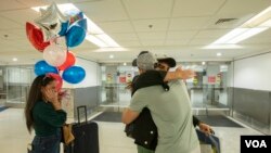 Edeitys Elián Coto Sierra mira a su hermano, Maikel Antonio Coto Salazar, de Cuba, quien llegó a Miami a través del programa de parole humanitario, y abraza a su amigo Yasser Dughman Cabrera, el viernes 17 de marzo de 2023. Foto: Alexia Fodere para Voz de América. 