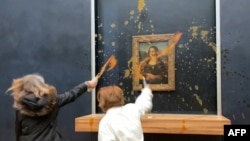This image grab taken from AFPTV footage shows two environmental activists from the collective dubbed "Riposte Alimentaire" (Food Retaliation) hurling soup at Leonardo Da Vinci's "Mona Lisa" painting, at the Louvre museum in Paris, Jan. 28, 2024. 