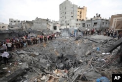 FILE - Palestinians inspect the rubble of a destroyed building after an Israeli airstrike in Deir al Balah, Gaza Strip on Oct. 27, 2023.