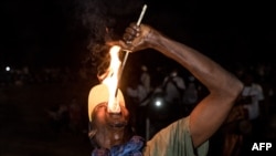 Un homme exécute une acrobatie avec du feu lors du festival du Kankurang à Janjanbureh, le 27 janvier 2024. (Photo MUHAMADOU BITTAYE / AFP)