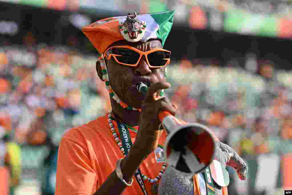 Un supporter ivoirien souffle dans une vuvuzela avant le match de football du groupe A de la Coupe d'Afrique des Nations (CAN) 2024 entre la Guinée équatoriale et la Côte d'Ivoire au stade olympique Alassane Ouattara à Ebimpe, Abidjan, le 22 janvier 2024.