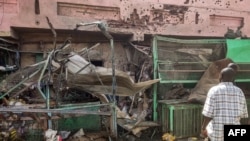FILE - People walk past a medical center building riddled with bullet holes at the Souk Sitta (Market Six) in the south of Khartoum, Sudan, on June 1, 2023.