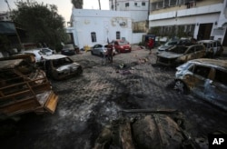 Palestinians check the site of the explosion at Ahli Arab Hospital in Gaza City, Oct. 18, 2023.