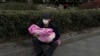 北京一家儿童医院外一名男子怀抱一个幼童。（2023年11月27日）