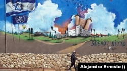 Un anciano camina junto a un mural pintado en lo que fue la estación de policía de Sderot totalmente destruida durante el ataque de Hamás.