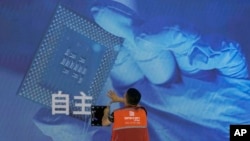 一名工人在上海舉辦的世界人工智能大會上檢查中國科技公司中科曙光展示的芯片和自主字樣的屏幕。（2023年7月5日）