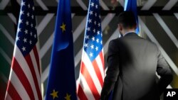 FILE - A worker adjusts the US and EU flags prior to the arrival of EU foreign policy chief Borrell and US Secretary of State Blinken during the EU-US Energy Council Ministerial meeting at the European Council building in Brussels, Apr. 4, 2023.