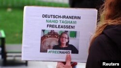 Potongan gambar dari sebuah video menunjukkan seorang demonstran memegang poster berisi tuntutan pembebasan warga Jerman keturunan Iran Nahid Taghavi, yang kini dipenjara di Iran, dalam sebuah aksi di Berlin, Jerman, pada 22 Februari 2023. (Foto: Reuters)