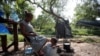 Pencari suaka asal Venzuela, Alejandra Pena, 34, memandikan anaknya Natanael, 1, di sebuah ember plastik di samping tenda mereka di kamp pengungsi di Matamoros, Meksiko, pada 20 Juni 2023. (Foto: Reuters/Daniel Becerril)