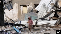 Seorang anak Palestina berjalan melewati pabrik yang hancur akibat pengeboman Israel di Jalur Gaza di Deir al Balah, 13 Januari 2024. (Foto: AP)