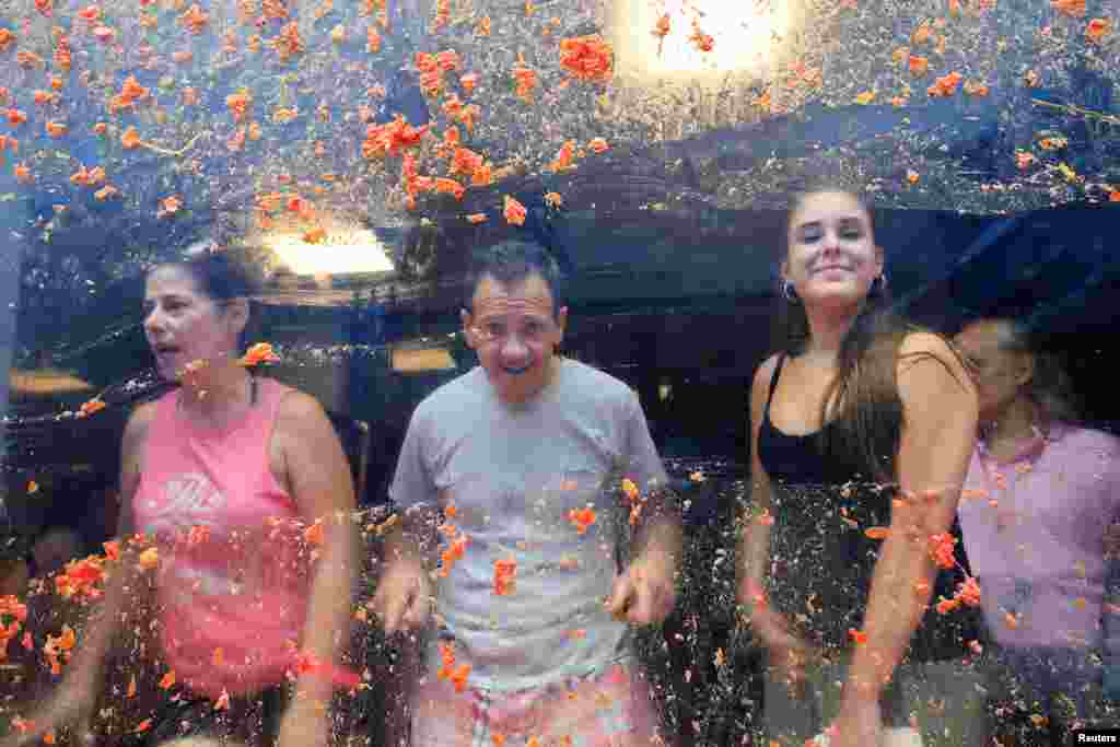 Residentes locais olham de uma janela coberta de polpa de tomate no dia do festival anual de luta de comida “La Tomatina” em Bunol, perto de Valência, Espanha, 28 de agosto de 2024.