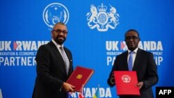 Secretário do Interior britânico, James Cleverly (esq), e o ministro das Relações Exteriores de Ruanda, Vincent Biruta, (dir) trocam documentos após assinarem um novo tratado, em Kigali, 5 de dezembro de 2023