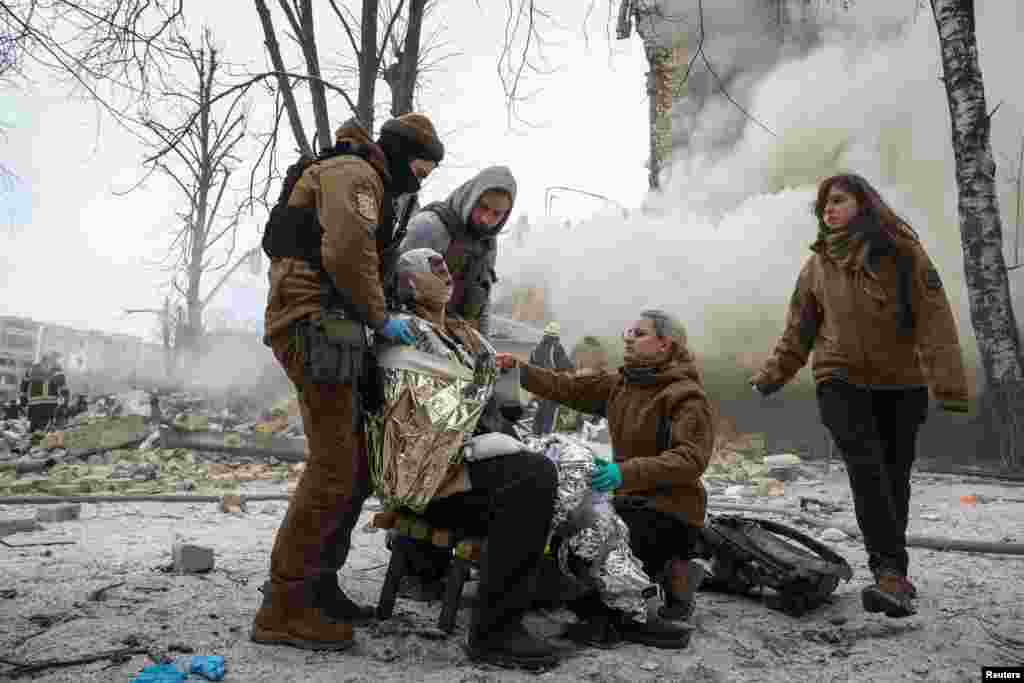 Medical workers treat a wounded local resident at a site of residential buildings heavily damaged during a Russian missile attack, in Kharkiv, Ukraine, Jan. 23, 2024.