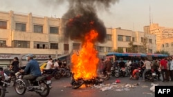Una foto obtenida por AFP fuera de Irán muestra a un grupo de personas alrededor de una moto incendiada en Teherán el 8 de octubre de 2022.
